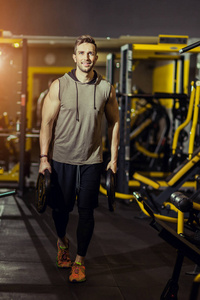 概念力量健康生活方式运动强壮肌肉男在健身房锻炼，用重量盘做冲刺练习