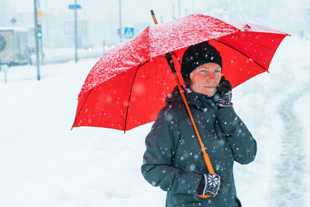 担心的女人在雪地里在红伞下用手机说话