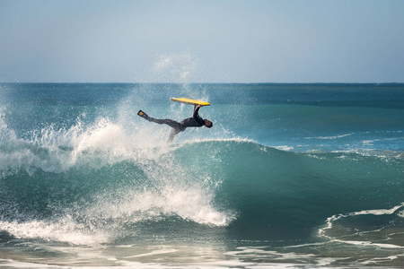 冲浪者在靠近海岸的一个大波浪上跳跃,海面是蓝色的,绿松石的阳光反射