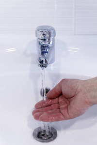 s hand touches the temperature of the water in the tap, against 