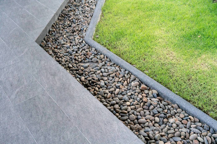 人行道和草坪之间装饰着黑色和棕色的石头. 景观设计细节.