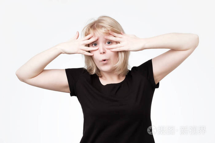 害羞的胆小少女用双手捂住脸, 通过手指偷看镜头