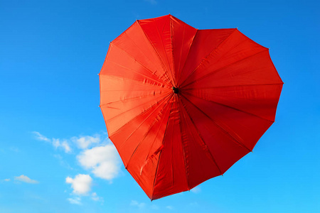 心在天空中在晴朗,阳光明媚的日子里, 红色,朱红色的伞在蔚蓝的天空中