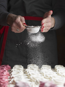 棉花糖的制作过程。 用金属筛把厨师的手关起来，在糕点店的厨房里用粉状糖洒上拉链。 糖果洒糖粉糖果