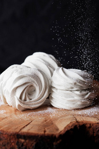 在糕点店厨房制作泽菲棉花糖的过程。 自制白色棉花糖在粉状糖木背景。 食物摄影。 用粉状糖粉尘的Zephyr。