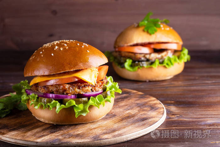 两个自制的汉堡包与牛肉和黄瓜在木背景