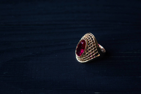 金色的戒指，红色的石头孤立在黑色的背景上