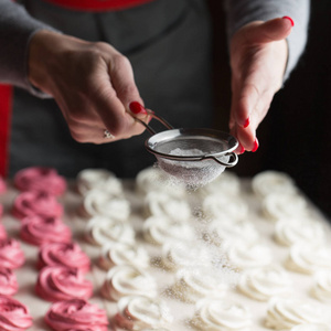 棉花糖的制作过程..在糕点店的厨房里，用金属筛将粉末状的糖洒上香喷喷的厨师的双手。糖果洒糖粉糖果