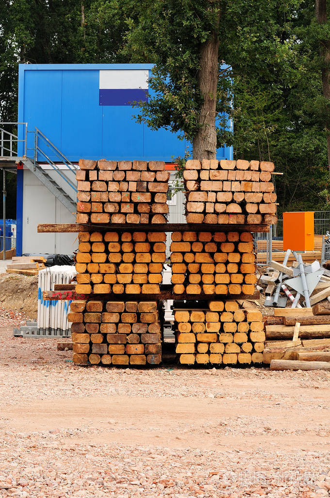 建筑工地蓝色容器和堆放在砾石地板上的木材
