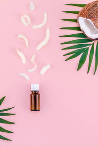 创意平躺顶部的绿色热带棕榈叶椰子水果和椰子油化妆品皮肤和头发护理粉红色纸背景复制空间。 最小热带夏季美容SPA概念