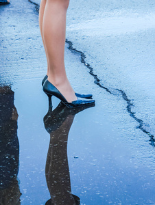 穿鞋的女人站在水坑里.照片