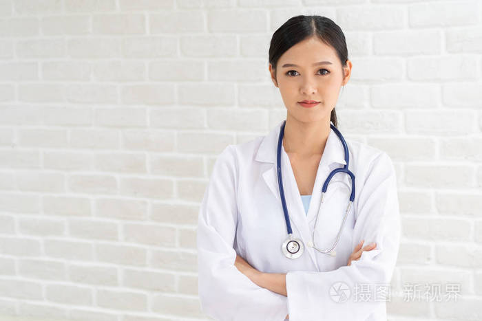 微笑的美丽的亚洲女医生的特写肖像,双臂交叉站立.