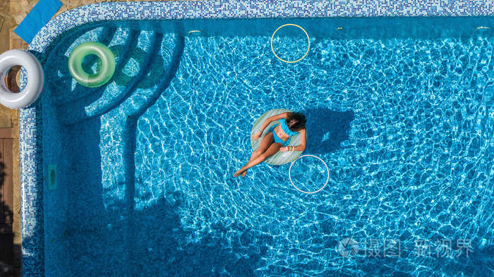 从上面看游泳池中美丽女孩的鸟瞰,在充气环形甜甜圈上游泳,在热带度假