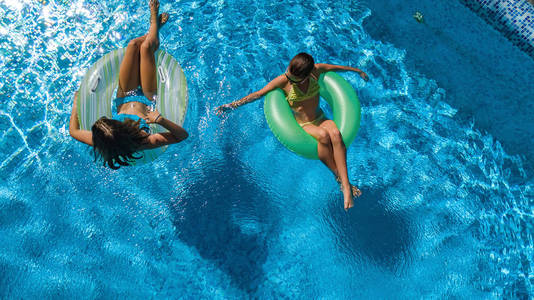 活跃的儿童游泳池，从上面俯瞰，快乐的孩子在充气环形甜甜圈上游泳，在度假胜地的家庭假日度假中在水中享受乐趣。