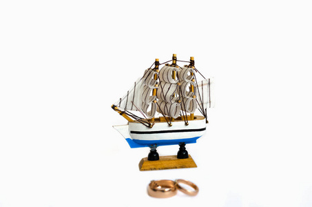 帆船模型与结婚戒指查出在白色背景