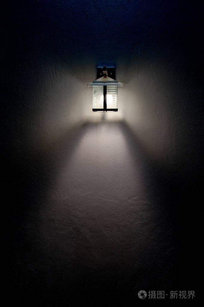 方形玻璃灯在黑暗中照亮了白色墙壁上的光束.