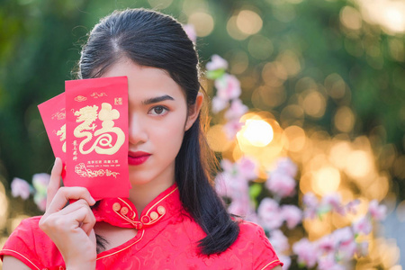 穿着中国血统红裙子的亚洲女孩对带美元的红包很满意