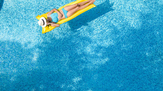 美丽的年轻女孩在游泳池放松，在充气床垫上游泳，在家庭度假的水中享受乐趣，热带度假胜地，空中无人机从上面观看