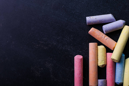 五颜六色的蜡笔躺在黑色粉笔板上复制空间。 学校教育和童年的概念。