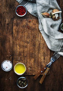 食品烹饪背景垂直模板。 在乡村木制桌子背景上提供切割板，叉子，香料，盐，橄榄油，餐巾纸。 上文视