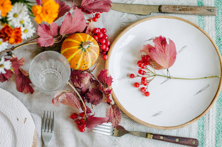 秋天的桌子设置与美丽的盘子，南瓜和鲜花秋天的家庭装饰为节日晚餐。