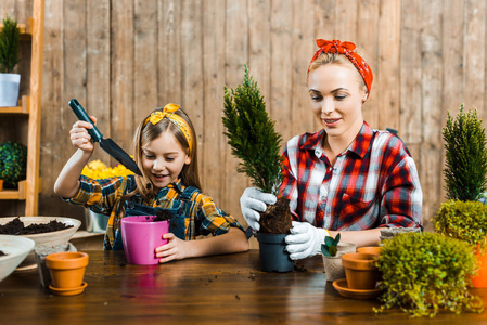 可爱的女儿旁边的一个可爱的女人在花盆里移栽绿色植物