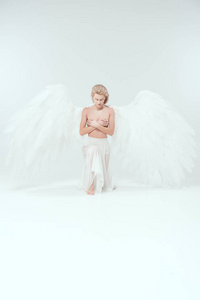 美丽温柔的女人，有天使的翅膀，遮住乳房，摆出孤立的白色姿势