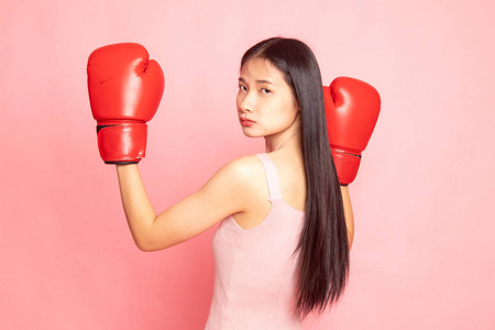 带红色拳击手套的年轻亚裔女子，粉红色背景