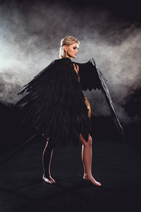 美丽的女人，有黑色的天使翅膀和剑，摆在黑色的背景上