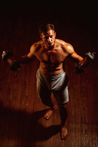 提高和变得更强。肌肉发达的人在健身房锻炼。人练习哑铃的重量。健康肌肉发达的工人。强壮的工人, 有六包腹肌. 健身和肌肉训练