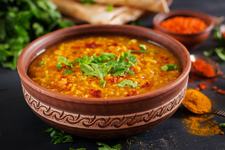 印度。传统的印度汤扁豆。印度Dhal辣咖喱碗，香料，草药，乡村黑色木制背景。正宗印度菜。间接费用