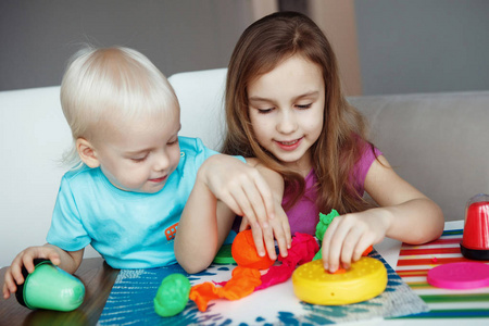 男孩和女孩坐在家里的桌子上玩橡皮泥