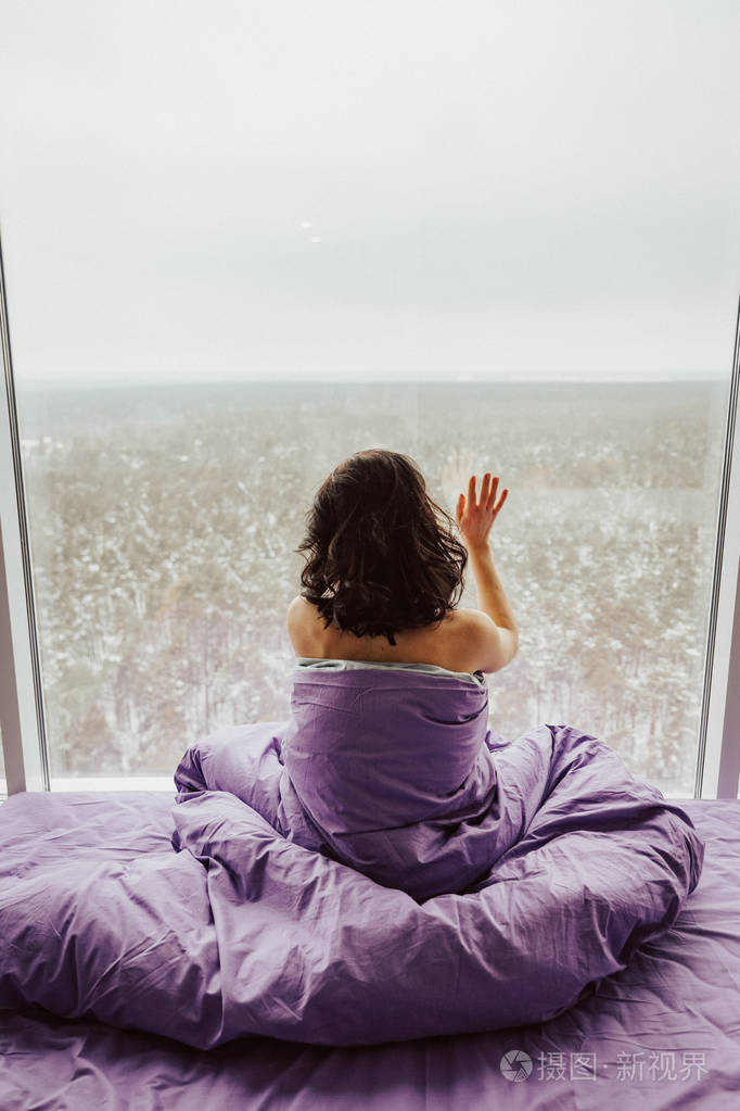 年轻的黑发女人在窗户旁边醒来