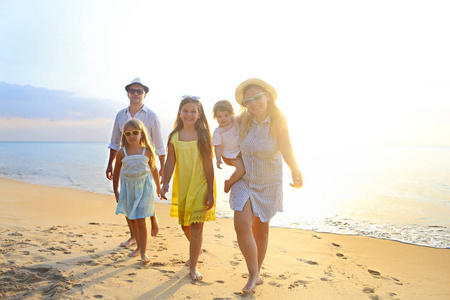 快乐的年轻家庭在海滩上玩得开心，在日落时跑步和跳跃