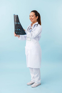 一位年轻快乐的女医生用x射线在蓝色墙壁背景上摆出孤立的姿势的照片。