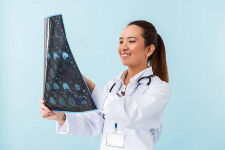 一位年轻快乐的女医生用x射线在蓝色墙壁背景上摆出孤立的姿势的照片。