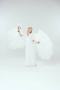 带翅膀的眼睛美丽的女人,穿着天使的服装,带着翅膀,拿着烛台,蜡烛隔离