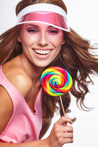 鲜艳的妆容。 美女肖像拿着五颜六色的棒棒糖。 粉红色的帽子。