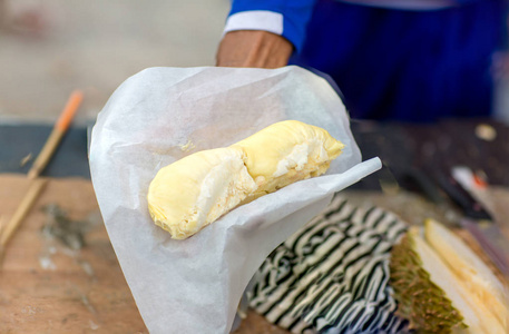 手拿榴莲剥榴莲黄肉,吃得很新鲜. 手显示黄色榴莲肉吃.