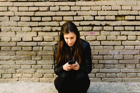 年轻的女人坐着用手机。
