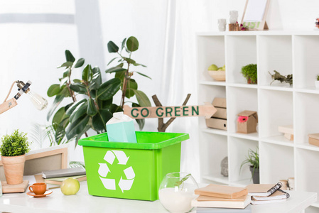 选择重点绿色回收箱与纸奶包装在办公桌上与绿色标志的背景环保理念