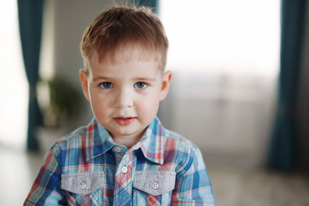 年轻可爱的金发男孩穿着格子衬衫，在室内微笑。 健康生活方式和青年的概念