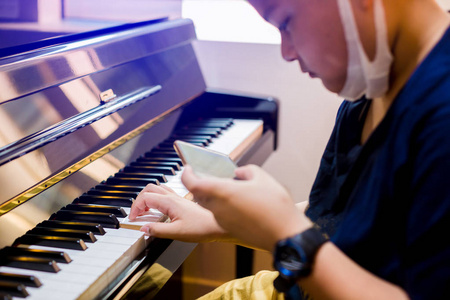 选择性的焦点，孩子弹钢琴与智能手机学习音乐。 有学习音乐的乐器。