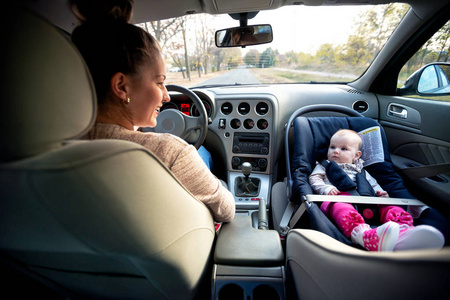 婴儿坐在婴儿车的前座上，和母亲一起开车