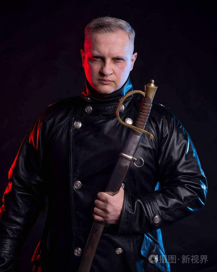 穿着黑色夹克的英俊男子手持黑色背景剑