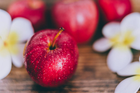 把红苹果贴在木桌上，用鲜花的概念，健康的食物成分