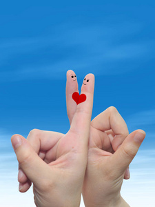 概念或概念人类或女性的双手，用两个手指涂着红色的心，在云蓝色的天空背景上微笑着的脸