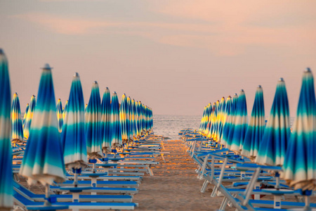 意大利里米尼。 晚上带蓝色太阳伞的里米尼海滩。 里米尼海滨。 意大利著名的度假胜地。