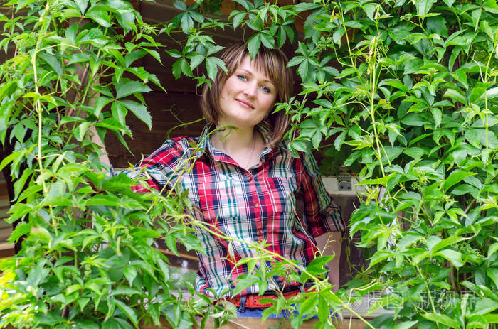 美丽的女人在绿色藤本的背景上微笑