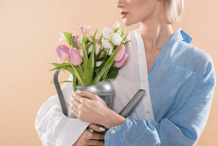 年轻女子手持浇花罐，站在生态服装中，隔离米色环保理念